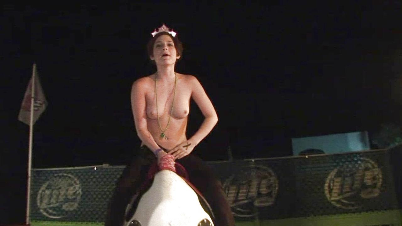 Three topless brunettes ride a mechanical bull